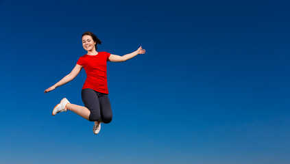 Obraz premium Teenage girl jumping outdoor against blue sky