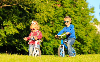 little boy and toddler girl on bikes in summer