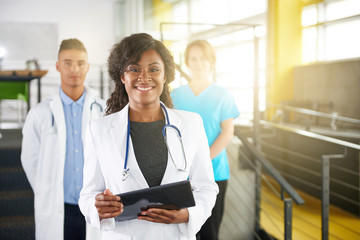 Portrait of a friendly female african american doctor and team in bright modern office