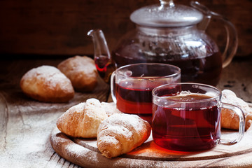 Ceylon black tea in glass cups with kettle, fresh croissants, vi