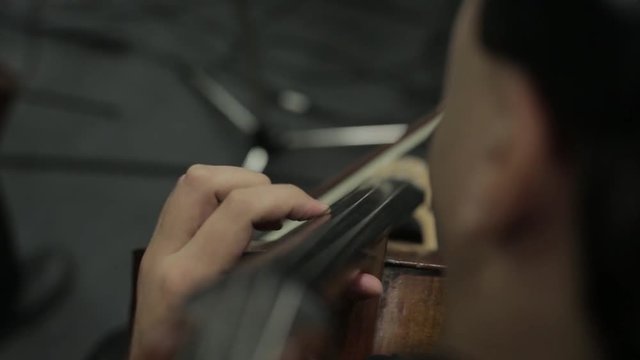 Symphony orchestra on stage, hands playing violin
