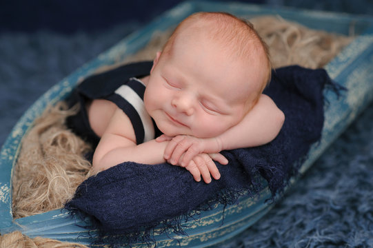 Smiling Newborn Baby Boy Sleeping in a Boat