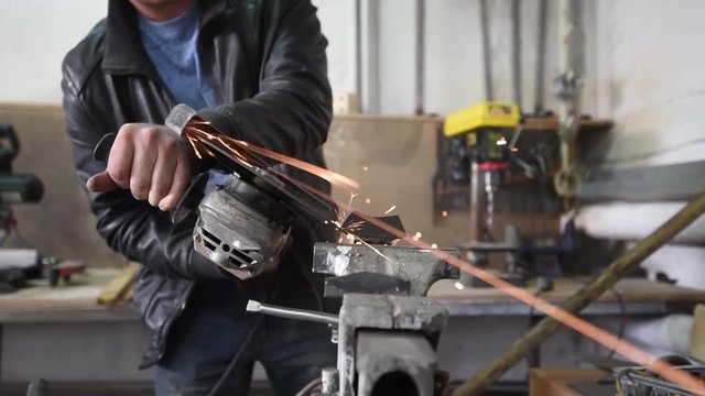 Worker with Angle Grinder does Metalworking in Industrial Environment