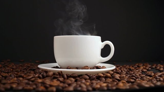 cup with hot drink on roasted coffee beans. dolly shot