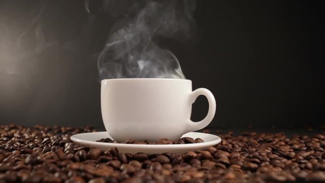 cup with hot drink on roasted coffee beans. dolly shot