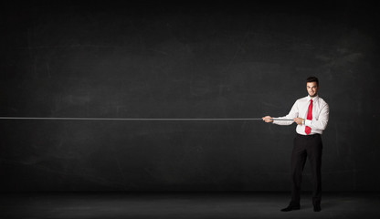 Obraz premium Businessman pulling rope on grey background