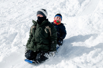 Fototapeta na wymiar Boys sledding fast down snowhill.