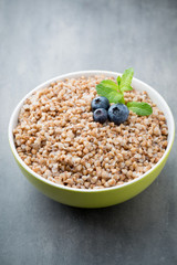 Buckwheat porridge in a bowl with mint leaves and blueberries.