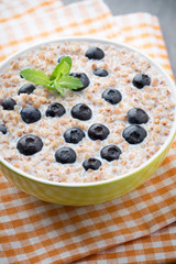 Buckwheat porridge in a bowl with mint leaves and blueberries.
