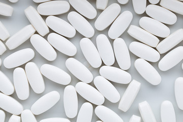 White pills on the white background.