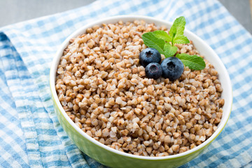 Buckwheat porridge in a bowl with mint leaves and blueberries.