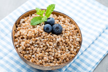 Buckwheat porridge in a bowl with mint leaves and blueberries.