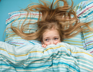 Little girl 5 years old with long blonde hair scared in the dream and woke up