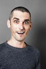 Obraz premium surprise concept - happy man with dark circles laughing to express his pleasure and amazement, grey background studio, contrast effects.
