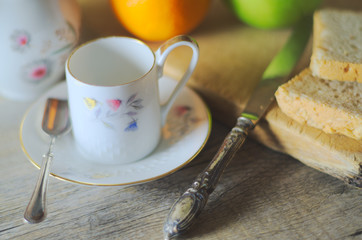 Morning breakfast in natural light on a wooden rustic table. Silverware, porcelain and fruits