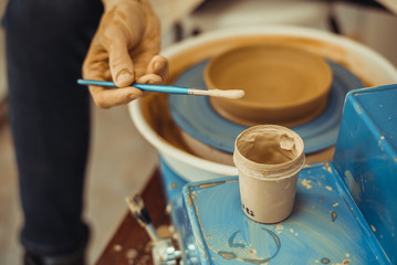 Fototapeta na wymiar man paints a clay plate