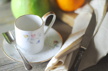 Morning breakfast in natural light on a wooden rustic table. Silverware, porcelain and fruits