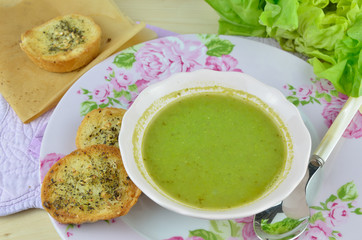 Bowl with fresh green pea soup (pottage) with pieces of garlic bread