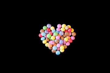 Cuore di confetti colorati ripieni di cioccolato su sfondo nero