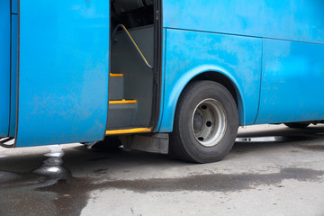 Blue bus at a station with door open, nobody