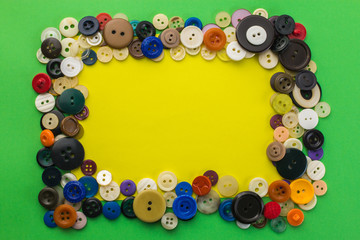 buttons and yellow sheet of paper on a green background