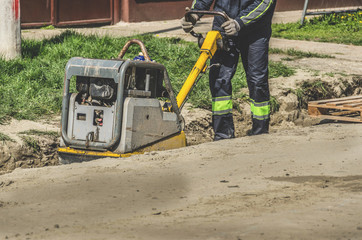 A worker with a vibrating plate in a ditch
