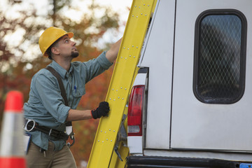 Caucasian worker loading ladder on truck