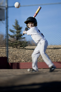 Boy hitting baseball on field