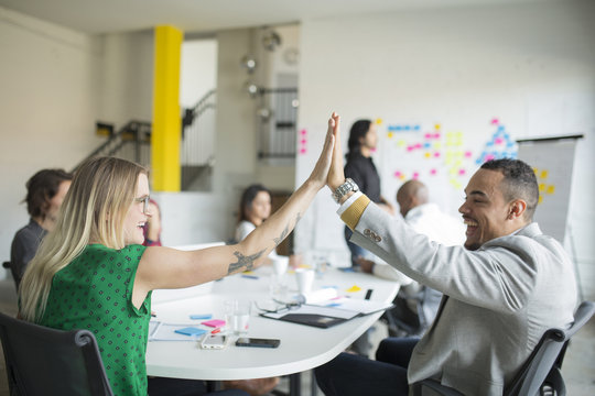 Business People High-fiving In Office Meeting