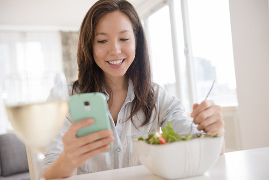 Mixed race woman photographing salad