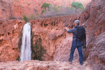 Man takes picture of Mooney Falls with his mobile phone
