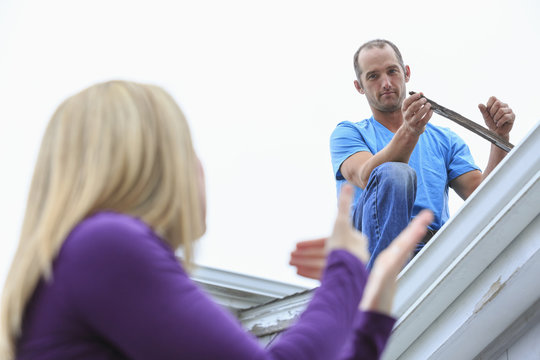 Caucasian homeowner signing to deaf roofer