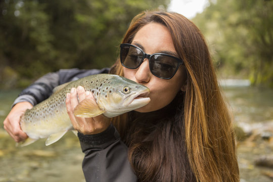 Caucasian woman kissing fish in remote river