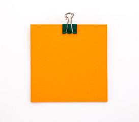 orange sheet of paper with green paper clip on a white background