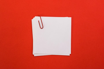 white sheet of paper with red paper clip on a red background