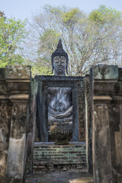 Big buddha image with green leafs background Sukhothai province Thailand.