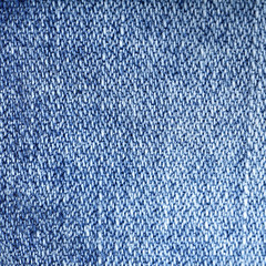 Jeans fabric background. Worn jean pants closeup of faded blue denim weave texture with vertical weave lines useful for elements of illustration, text copyspace or backgrounds.