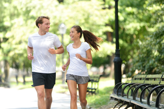 Runners Jogging Together In New York City Central Park, USA. Healthy Couple Of New Yorkers Athletes Friends Running In Summer Sun Working Out A Cardio Exercise On Manhattan, United Sates Of America.