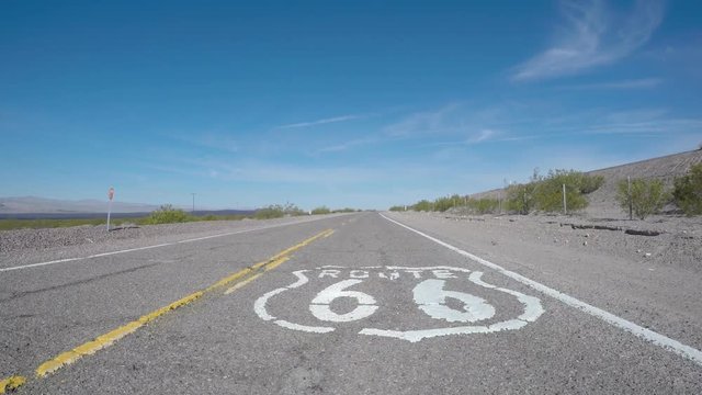 Route 66 rustict pavement sign driving shot near Barstow, California.