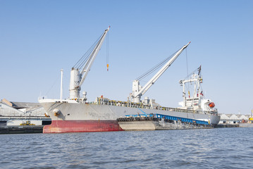 Fototapeta premium Container Cargo freight ship with working crane bridge in shipya