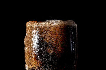 Soda large glass, overflowing glass of soda closeup with bubbles isolated on black background
