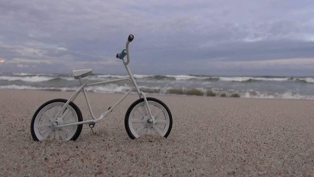 Toy bicycle in the sand on the beach by the sea on overcast day