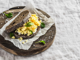 Scramble egg sandwich on rustic wooden background. Healthy breakfast or snack