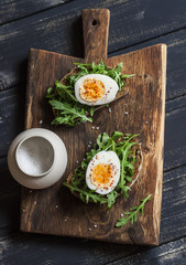 Sandwich with arugula, boiled egg and mustard on a wooden board. Healthy breakfast or snack