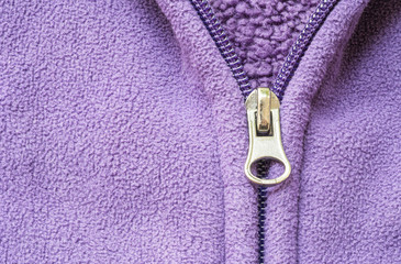 Closeup head of zipper at purple jacket textured background © kenkuza