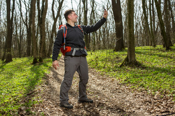 Man hiker taking photo with smart phone in forest