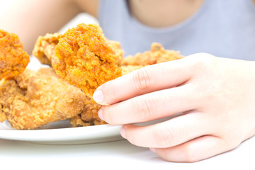 Woman holding and eatting fried chicken in white plate on white