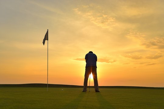 Young Man Playing Golf At Sunset