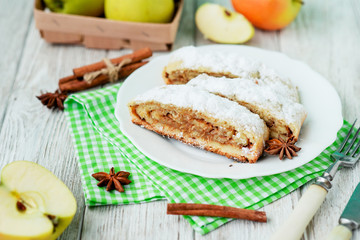 Fototapeta na wymiar dessert , apple strudel with cinnamon, sugar and spices on a wooden background 