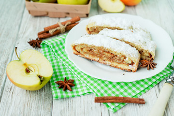 
dessert , apple strudel with cinnamon, sugar and spices on a wooden background   